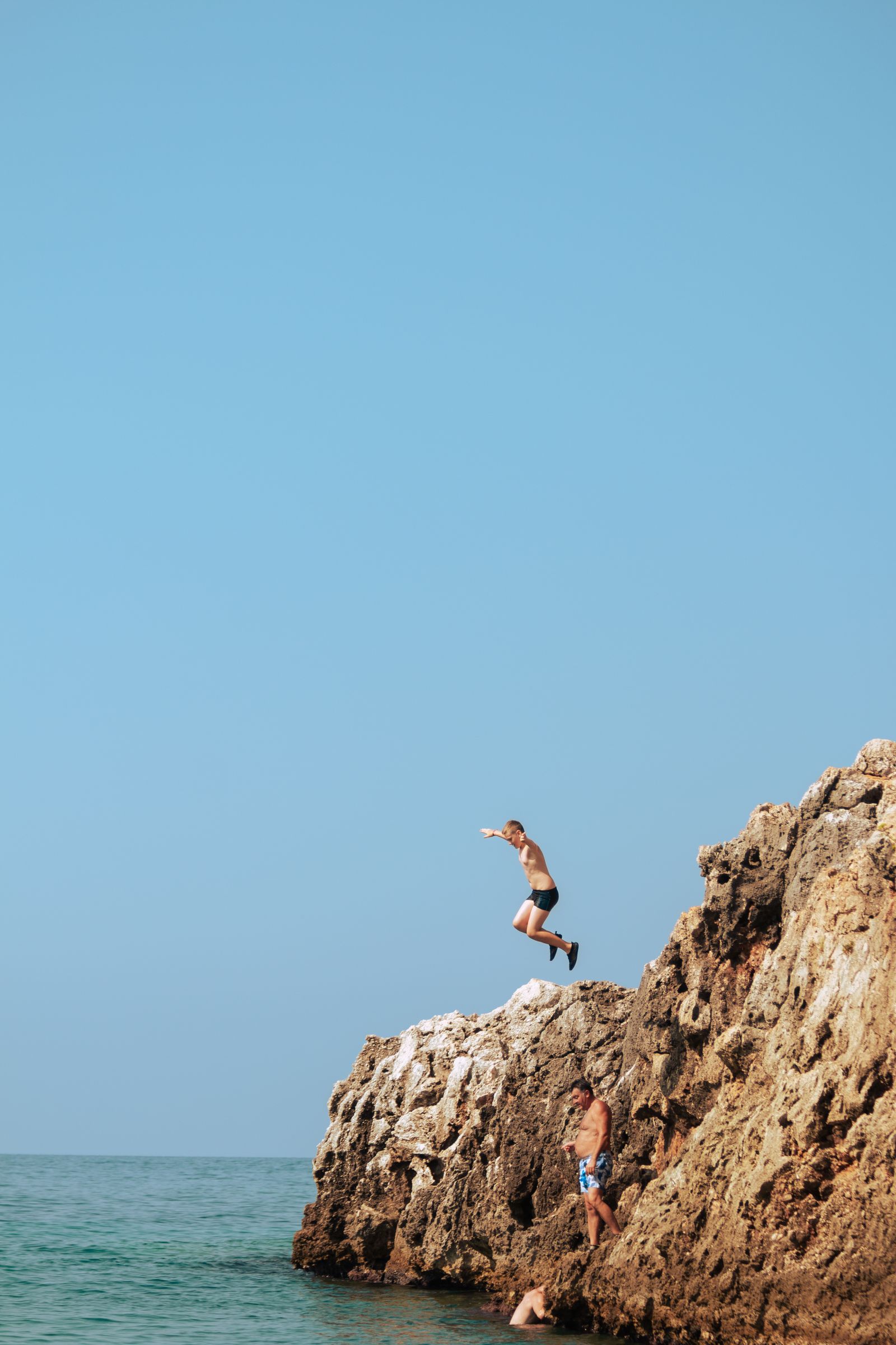 A guest leaping from a rock ledge into deep water